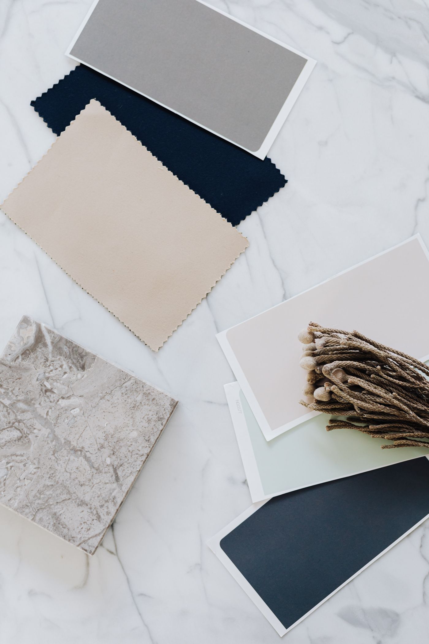 Neutral fabric, stone and colour samples arranged on marble